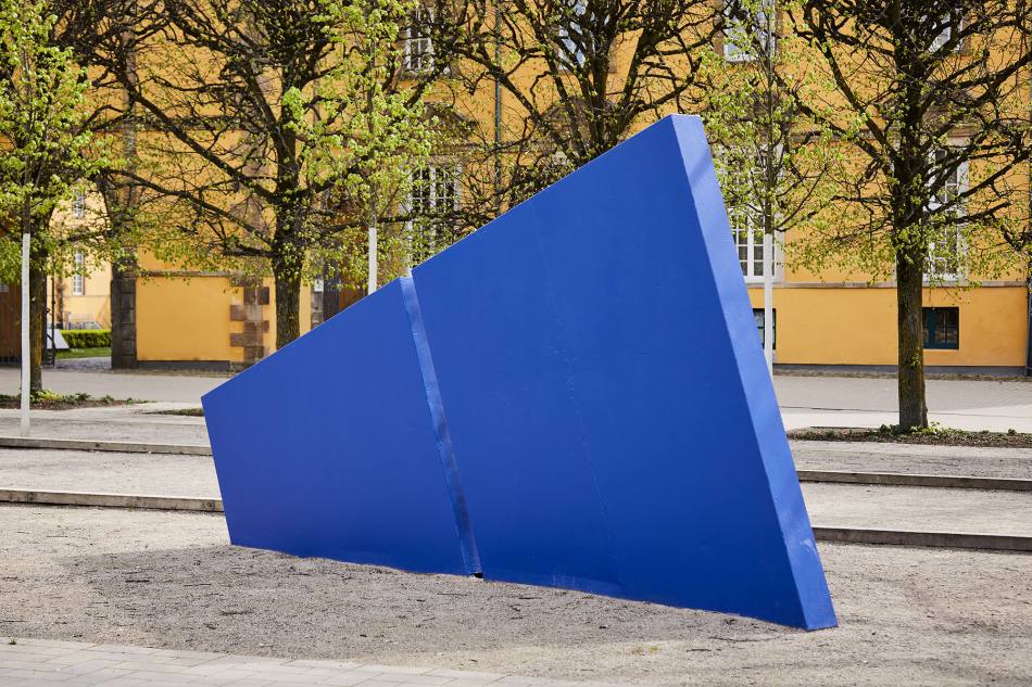 Ein blaues Dreieck, das wie ein Zacken aus der Erde ragt und in der Mitte geteilt ist.