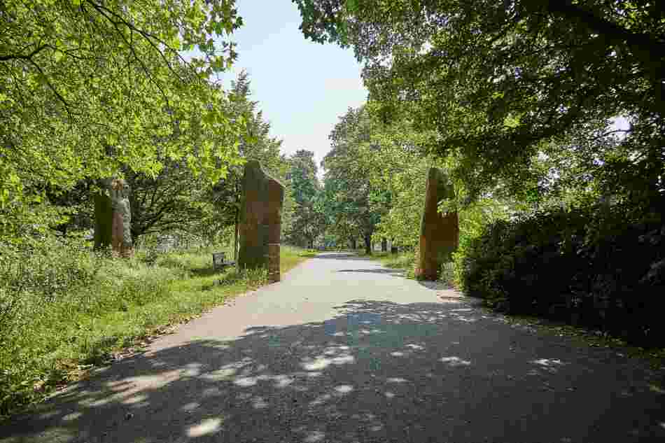 3 Große Quader aus Sandstein, die den Weg kreuzen. Am Rande des Weges stehen Bäume.