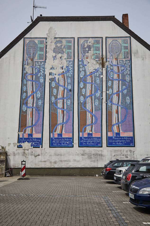 A large mural on the side wall of a residential building, consisting of 4 almost identically painted narrow panels with mysterious symbols and signs.