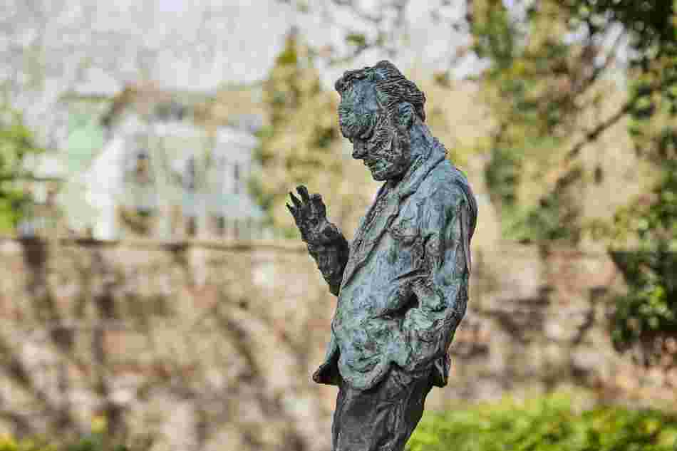 Seitenansicht der Skulptur, die den SPD-Politiker Willy Brandt darstellt: Seine rechte Hand hat er erhoben, als ob er spricht. Die andere Hand ist in der Tasche. Sein Blick ist nach unten gerichtet. Er sieht nachdenklich aus.